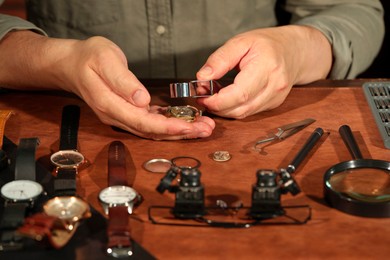 Photo of Man fixing mechanism of vintage wrist watch at table, closeup