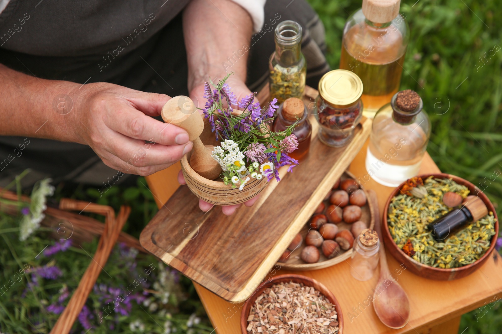 Photo of Senior woman with mortar and pestle making tincture outdoors, closeup