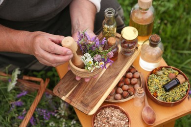 Photo of Senior woman with mortar and pestle making tincture outdoors, closeup