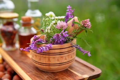 Photo of Tincture, wildflowers, mortar and pestle outdoors, closeup