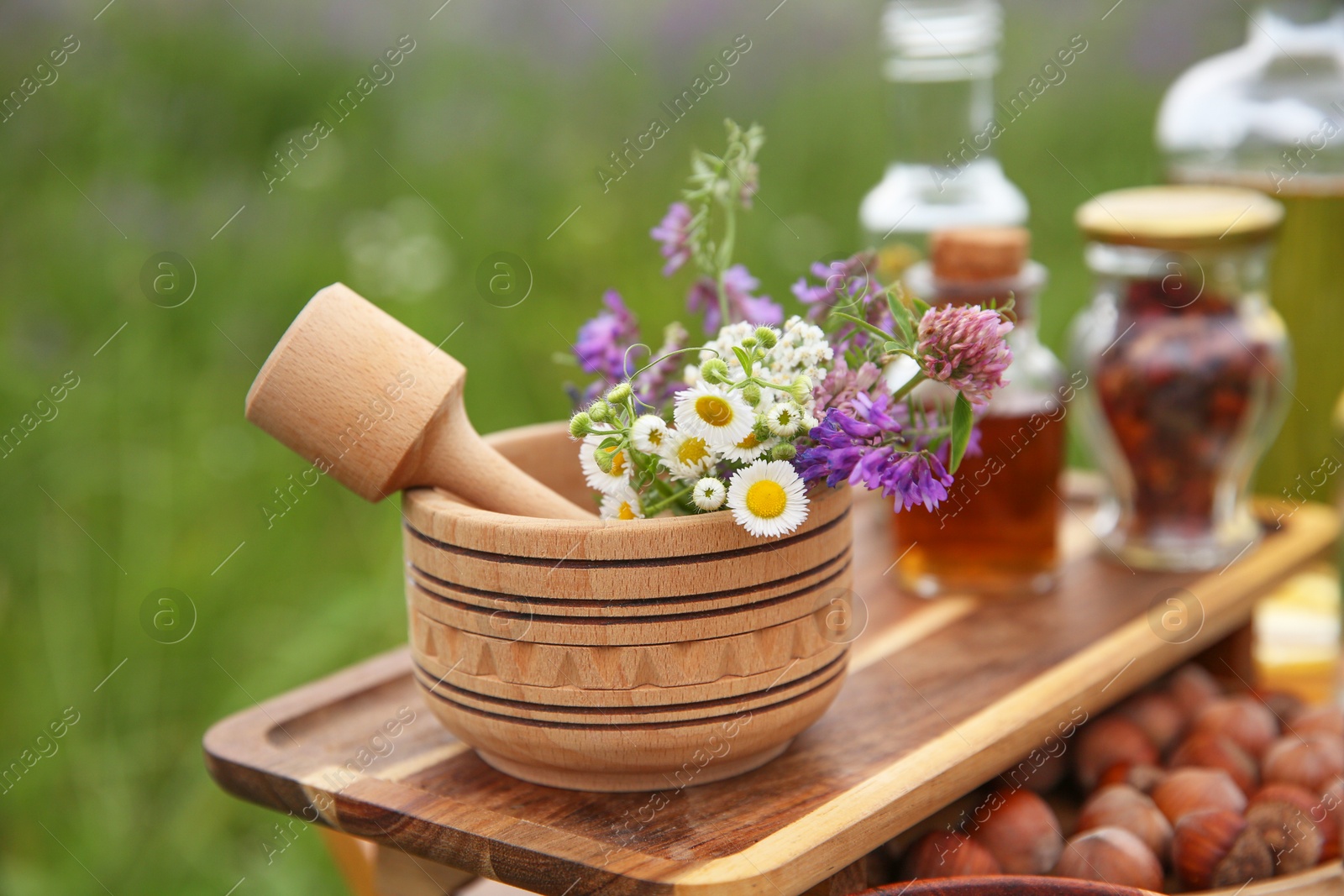 Photo of Tincture, wildflowers, hazelnuts mortar and pestle outdoors