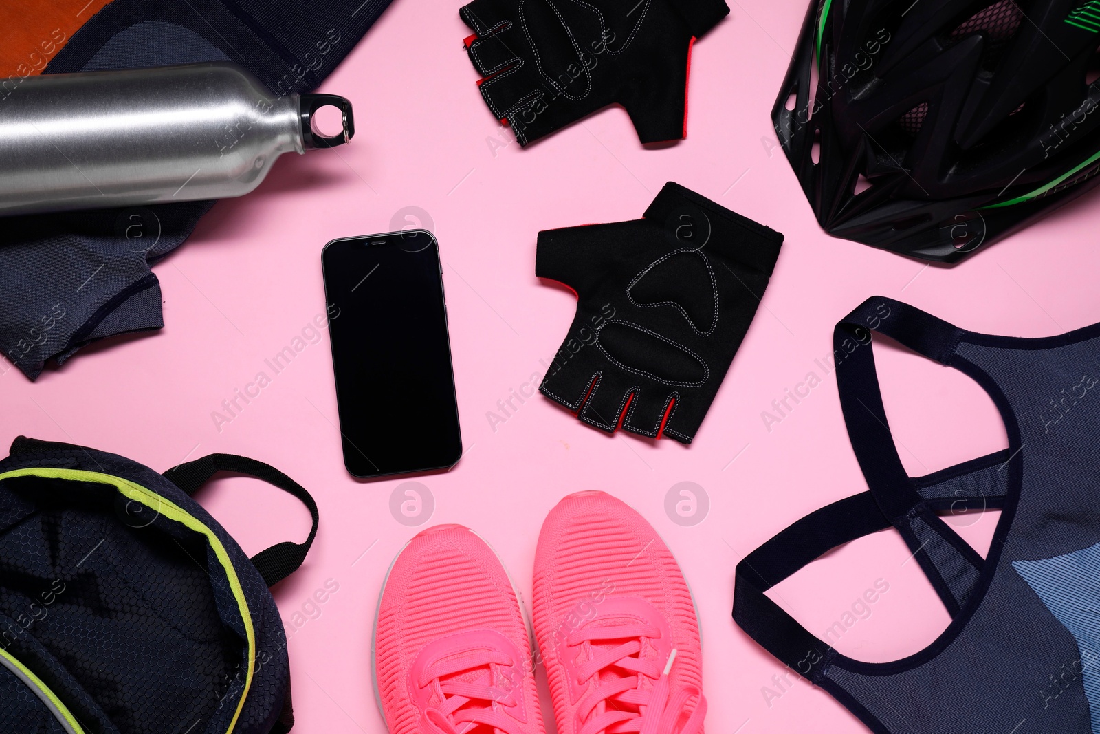 Photo of Bicycle helmet, sportswear, sneakers, thermo bottle and smartphone on pink background, flat lay