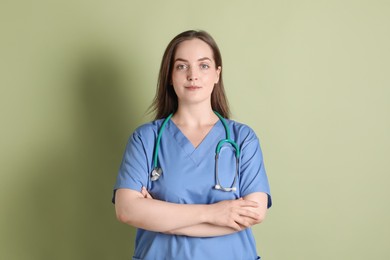 Professional nurse with stethoscope on pale green background