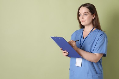 Professional nurse with clipboard on pale green background. Space for text