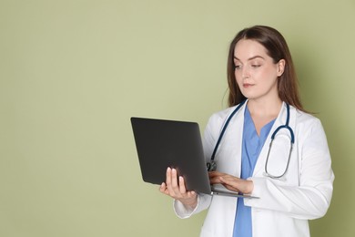 Photo of Professional nurse working with laptop on pale green background. Space for text