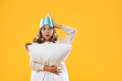 Overslept girl with sleep mask and pillow on orange background, space for text