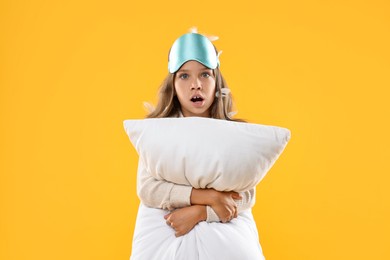 Photo of Overslept girl with sleep mask and pillow on orange background