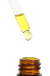 Photo of Dripping tincture from pipette into bottle on white background, closeup