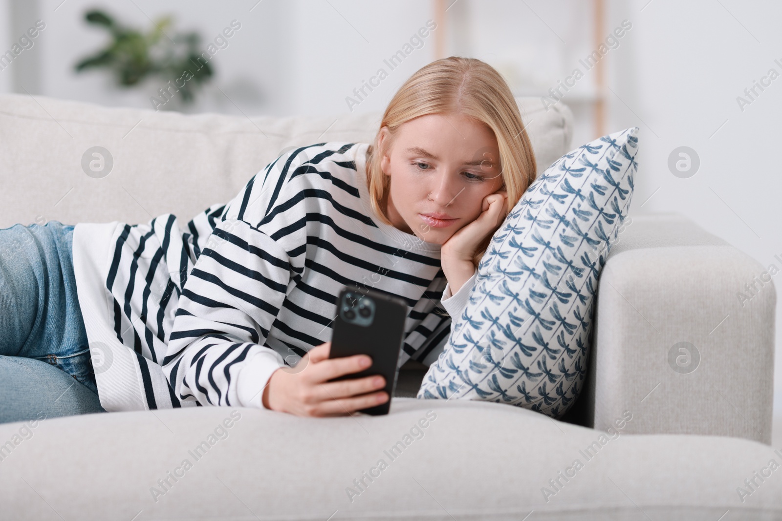 Photo of Beautiful woman using smartphone on sofa indoors