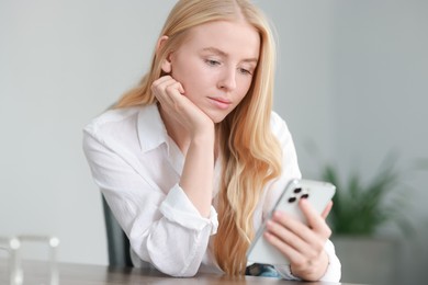 Beautiful woman using smartphone at table in office