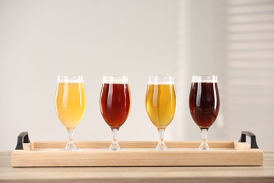 Photo of Glasses with different types of beer on wooden table indoors