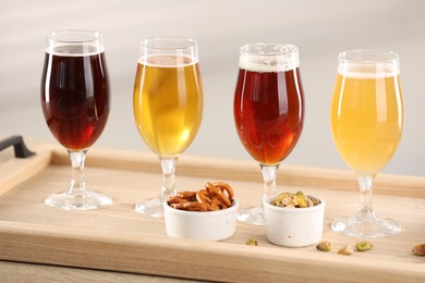 Photo of Glasses with different types of beer and snacks on wooden table indoors, closeup