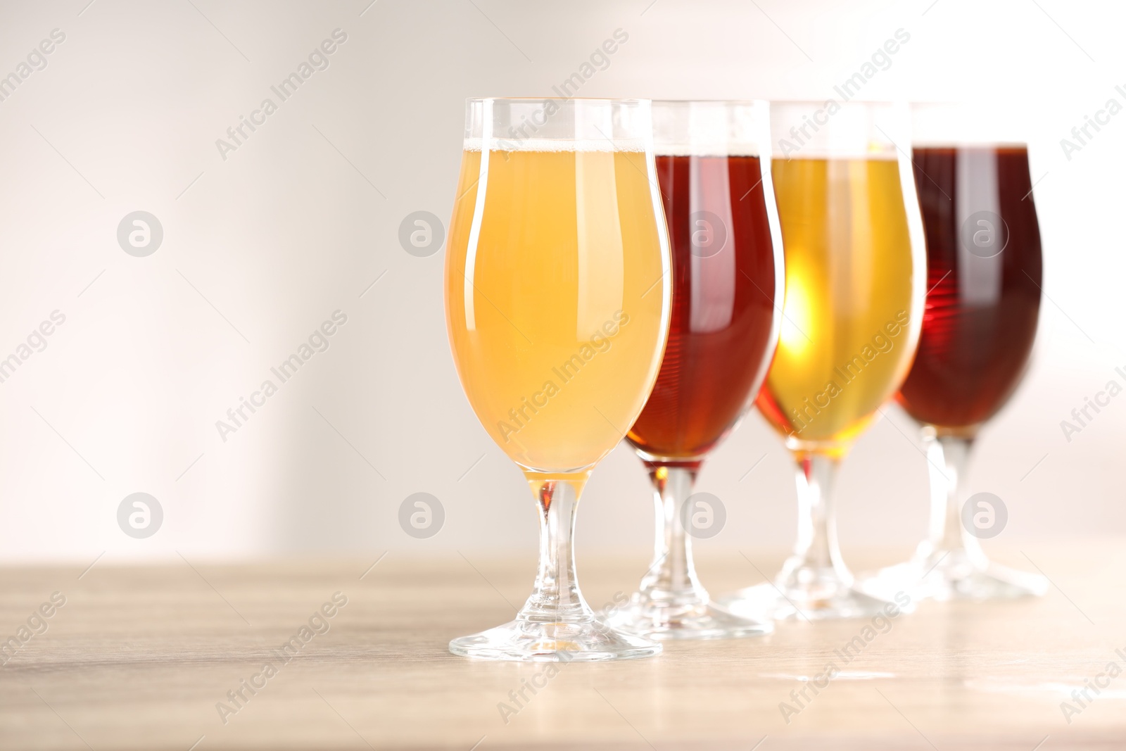 Photo of Glasses with different types of beer on wooden table indoors, closeup. Space for text