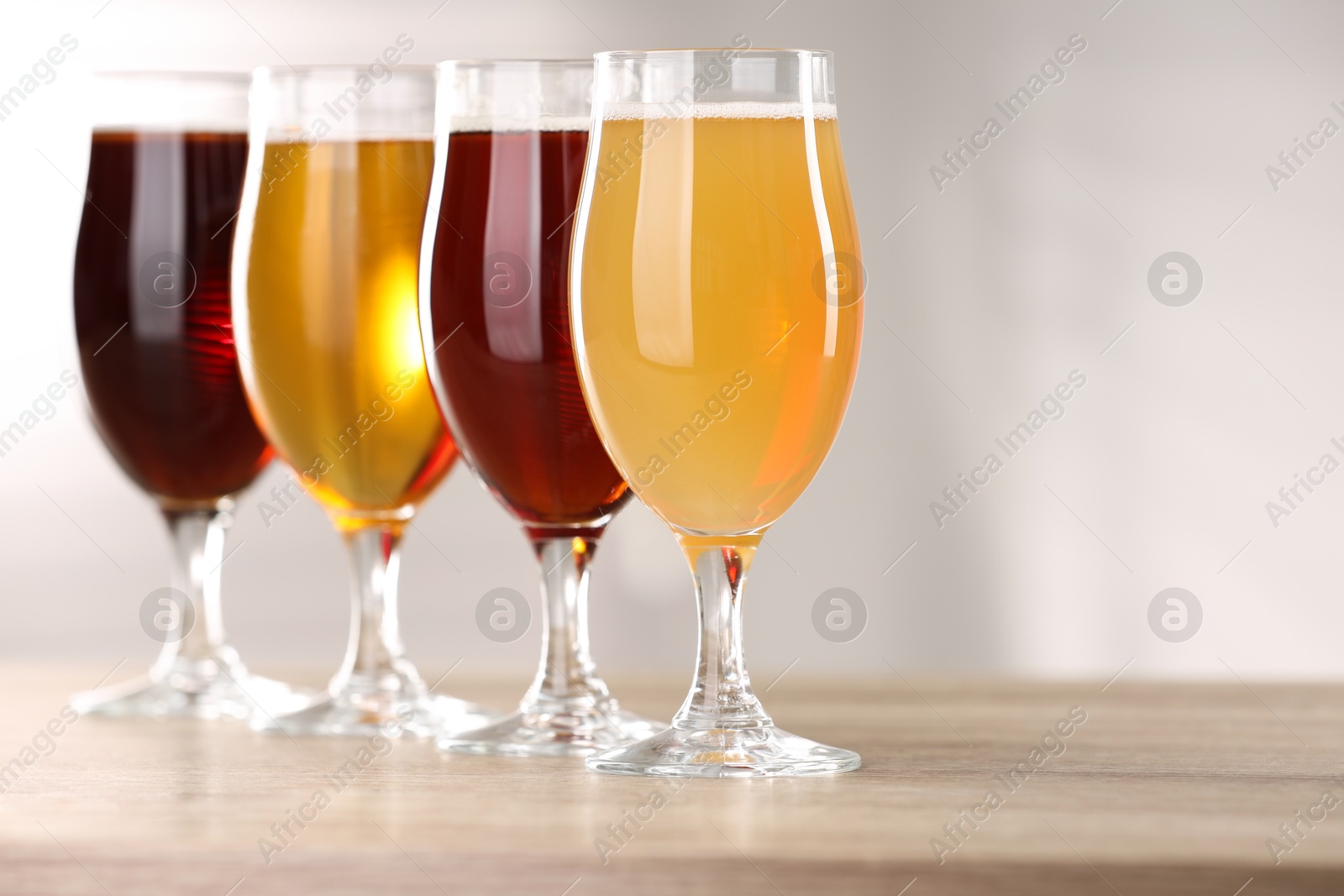 Photo of Glasses with different types of beer on wooden table indoors, closeup. Space for text