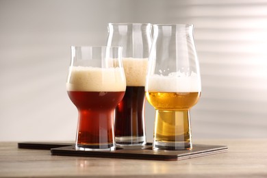 Photo of Glasses with different types of beer on wooden table indoors