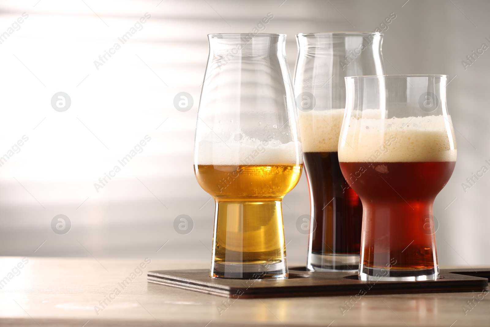 Photo of Glasses with different types of beer on wooden table indoors, space for text