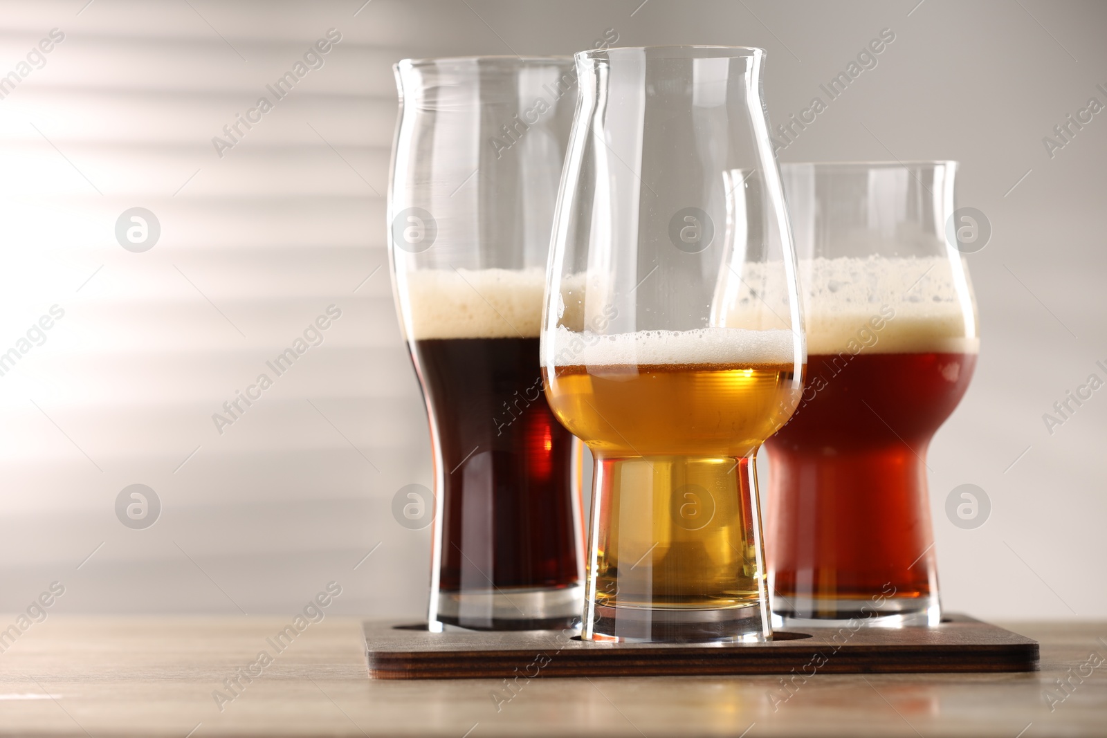 Photo of Glasses with different types of beer on wooden table indoors, closeup. Space for text