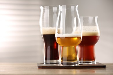 Photo of Glasses with different types of beer on wooden table indoors, closeup. Space for text