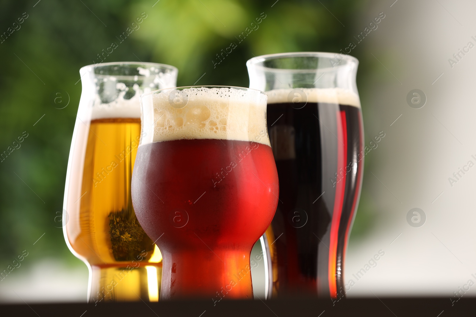 Photo of Glasses with different types of beer on table against blurred background, closeup