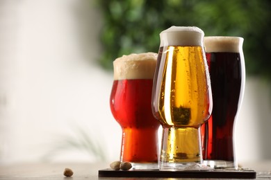 Photo of Glasses with different types of beer on table against blurred background, closeup. Space for text