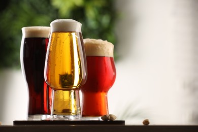 Photo of Glasses with different types of beer on table against blurred background, closeup. Space for text