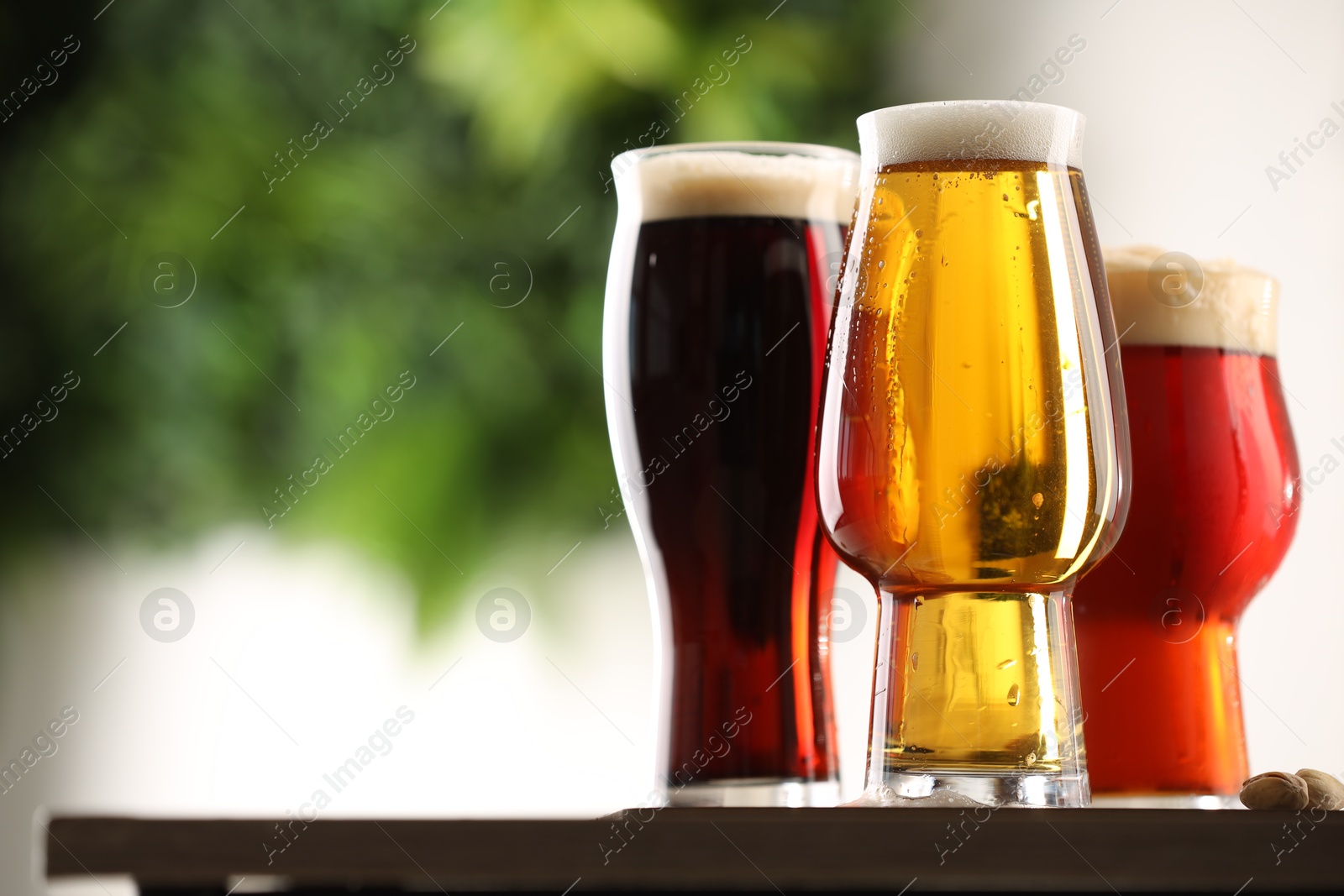 Photo of Glasses with different types of beer on table against blurred background, closeup. Space for text