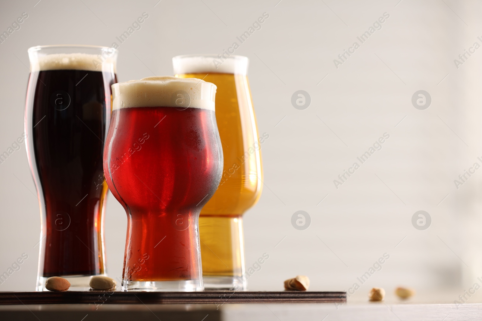 Photo of Glasses with different types of beer on table indoors, closeup. Space for text