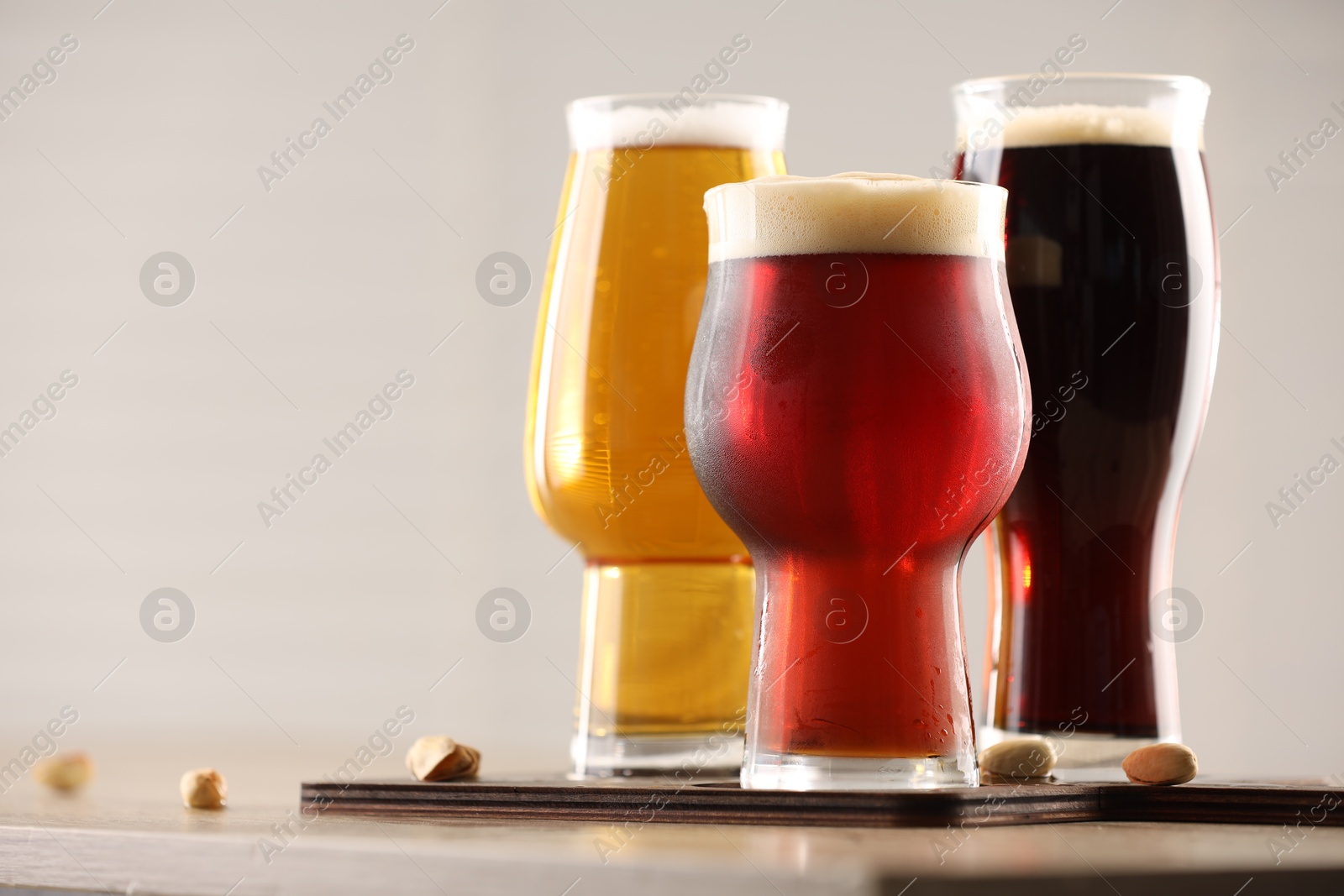 Photo of Glasses with different types of beer on wooden table indoors, closeup. Space for text