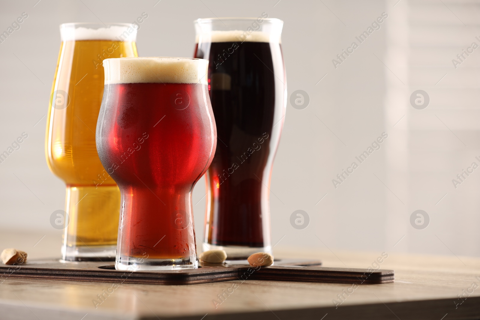 Photo of Glasses with different types of beer on wooden table indoors, closeup. Space for text