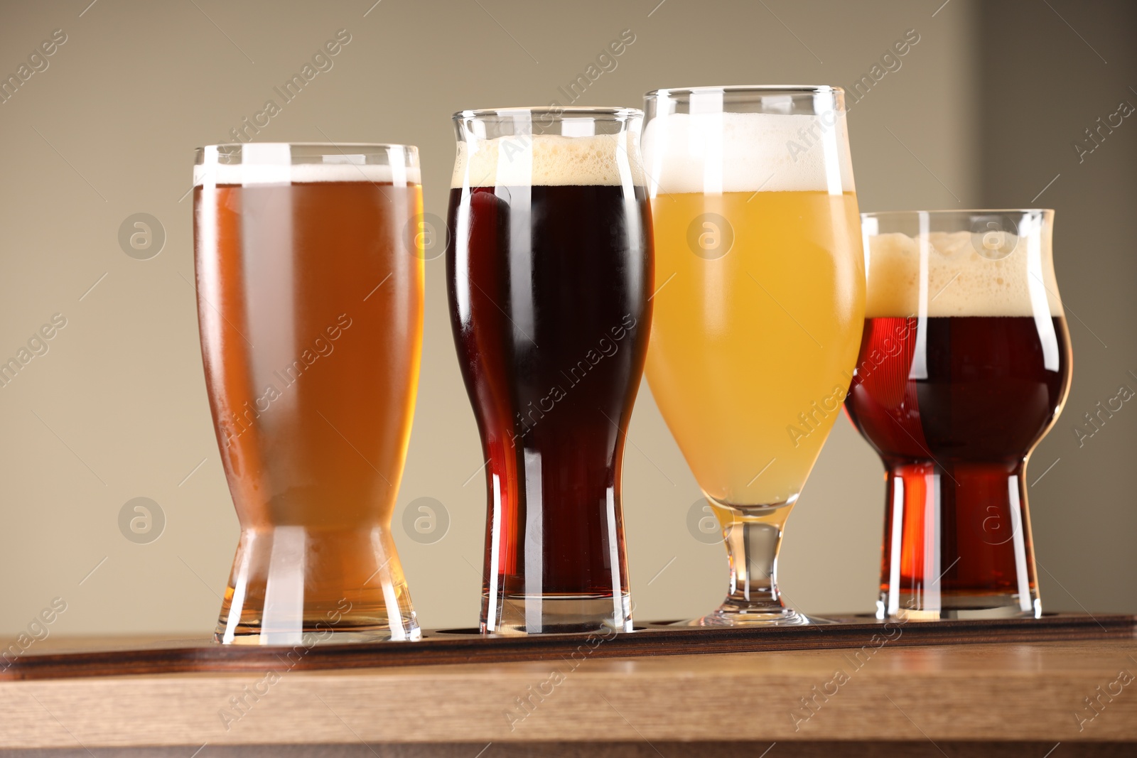 Photo of Glasses with different types of beer on wooden table indoors