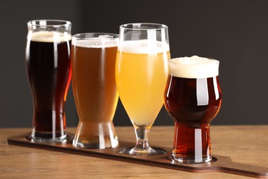 Glasses with different types of beer on wooden table indoors, closeup