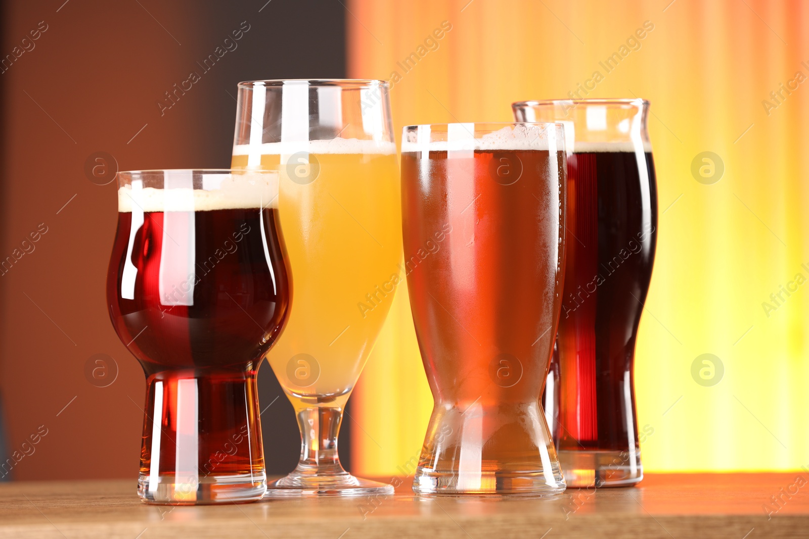 Photo of Glasses with different types of beer on wooden table indoors