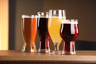 Photo of Glasses with different types of beer on wooden table indoors