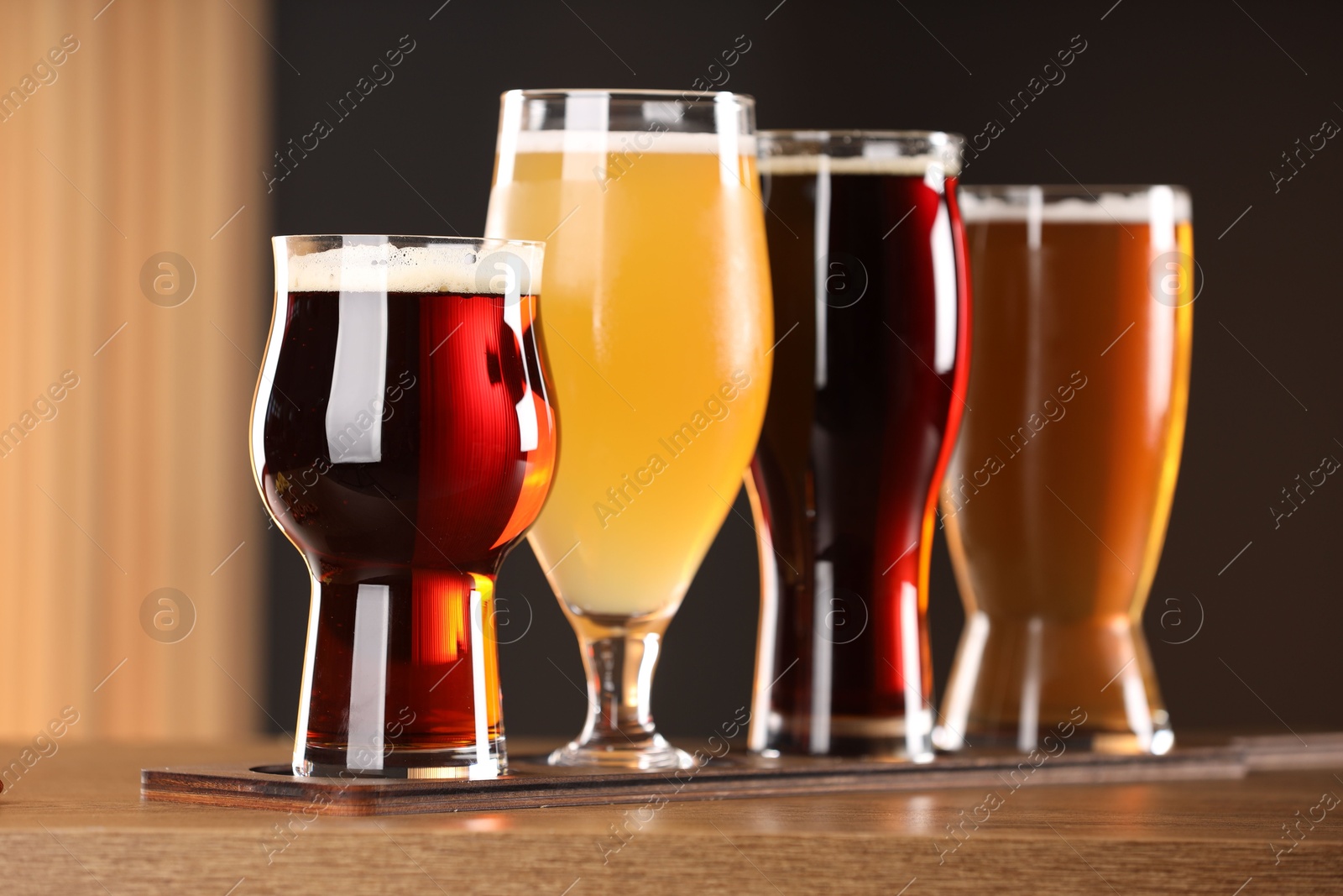 Photo of Glasses with different types of beer on wooden table indoors, closeup