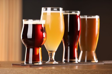 Photo of Glasses with different types of beer on wooden table indoors, closeup