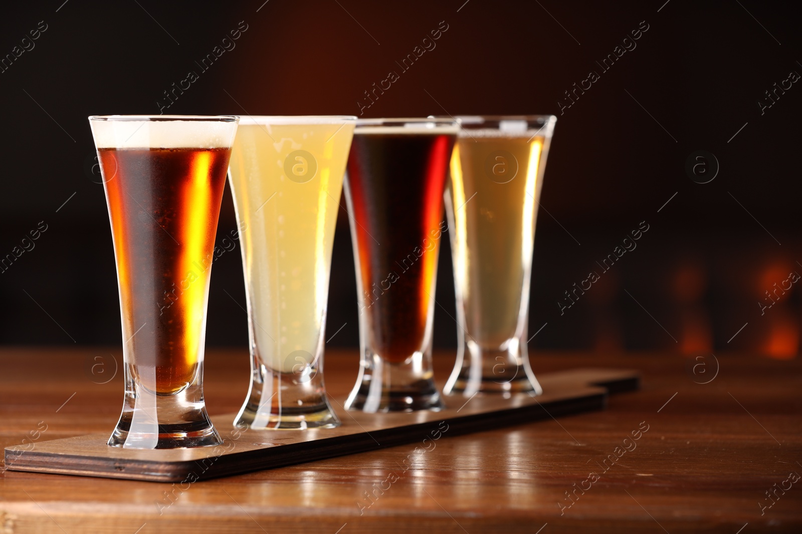 Photo of Glasses with different types of beer on wooden table against color background, closeup