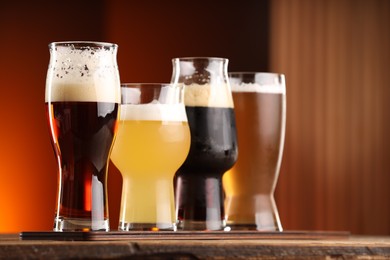 Photo of Glasses with different types of beer on wooden table indoors, closeup