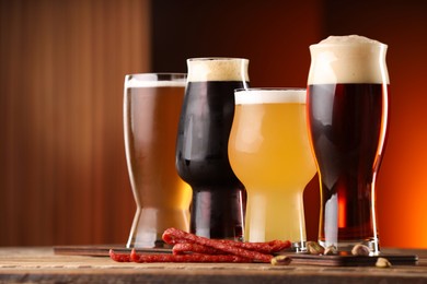 Photo of Glasses with different types of beer and snacks on wooden table indoors, closeup