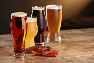 Photo of Glasses with different types of beer and snacks on wooden table