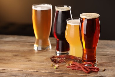 Photo of Glasses with different types of beer and snacks on wooden table