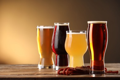 Photo of Glasses with different types of beer and snacks on wooden table against color background