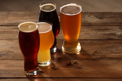 Photo of Glasses with different types of beer and pistachio nuts on wooden table