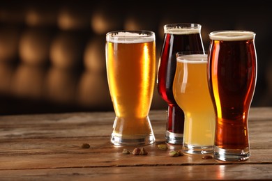 Photo of Glasses with different types of beer and pistachio nuts on wooden table indoors, space for text