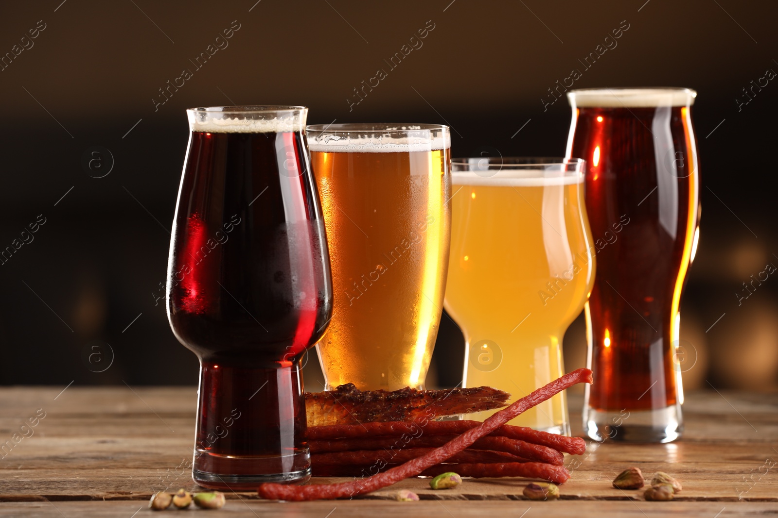 Photo of Glasses with different types of beer and snacks on wooden table indoors, closeup