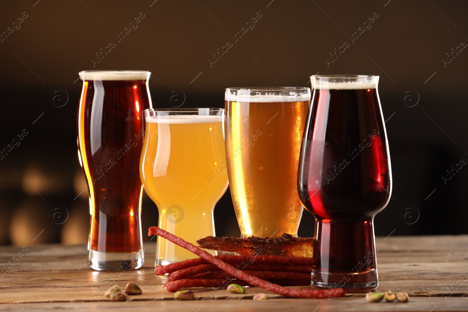 Photo of Glasses with different types of beer and snacks on wooden table indoors, closeup