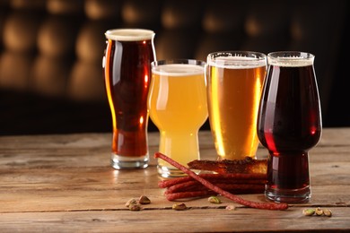 Glasses with different types of beer and snacks on wooden table indoors