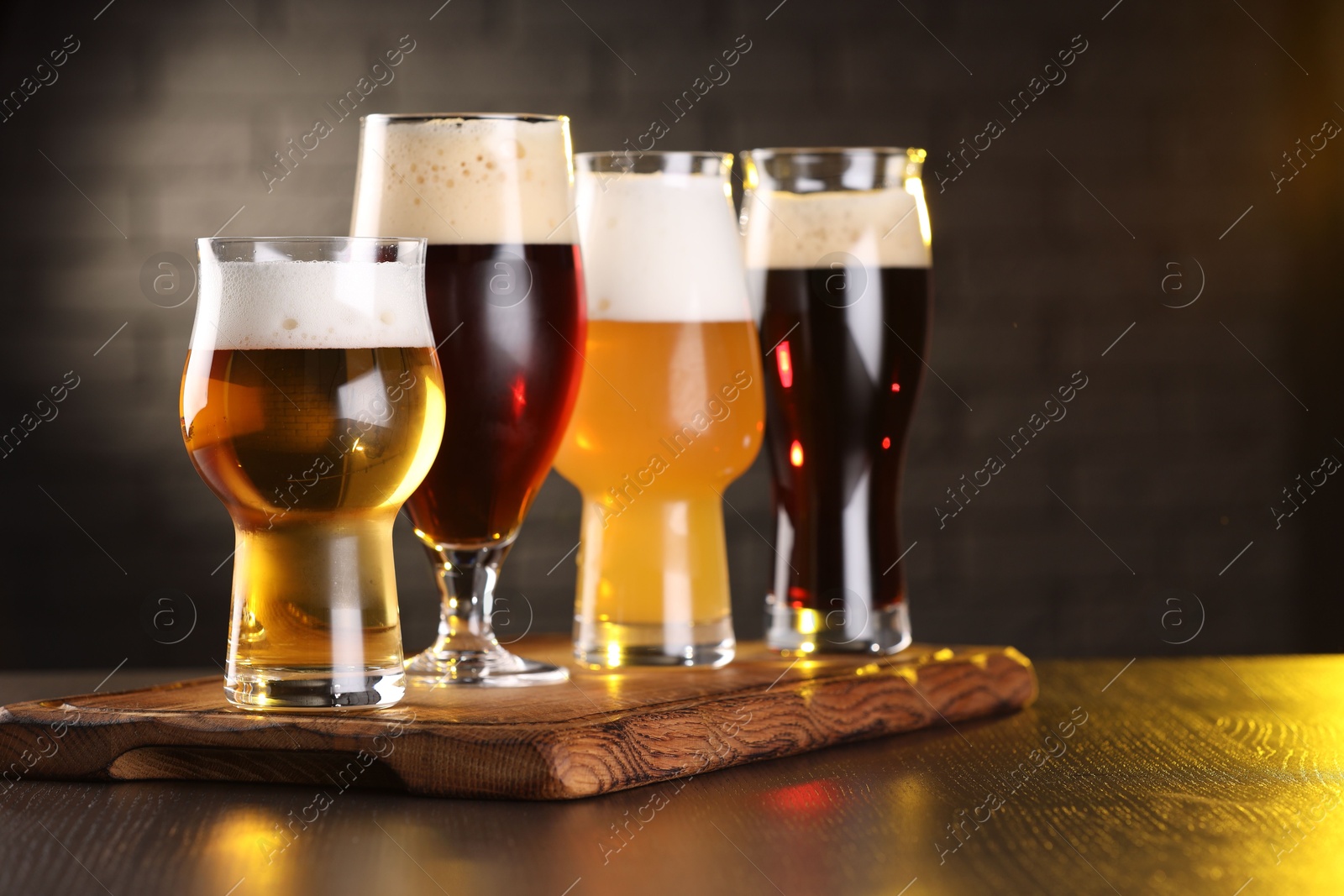 Photo of Glasses with different types of beer on wooden table in bar, closeup