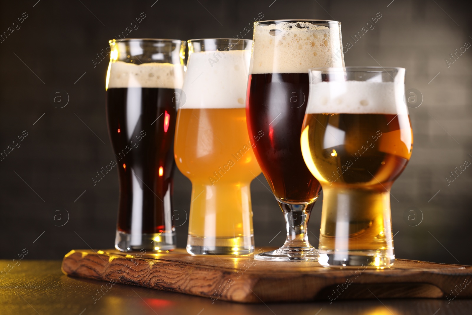 Photo of Glasses with different types of beer on wooden table in bar, closeup