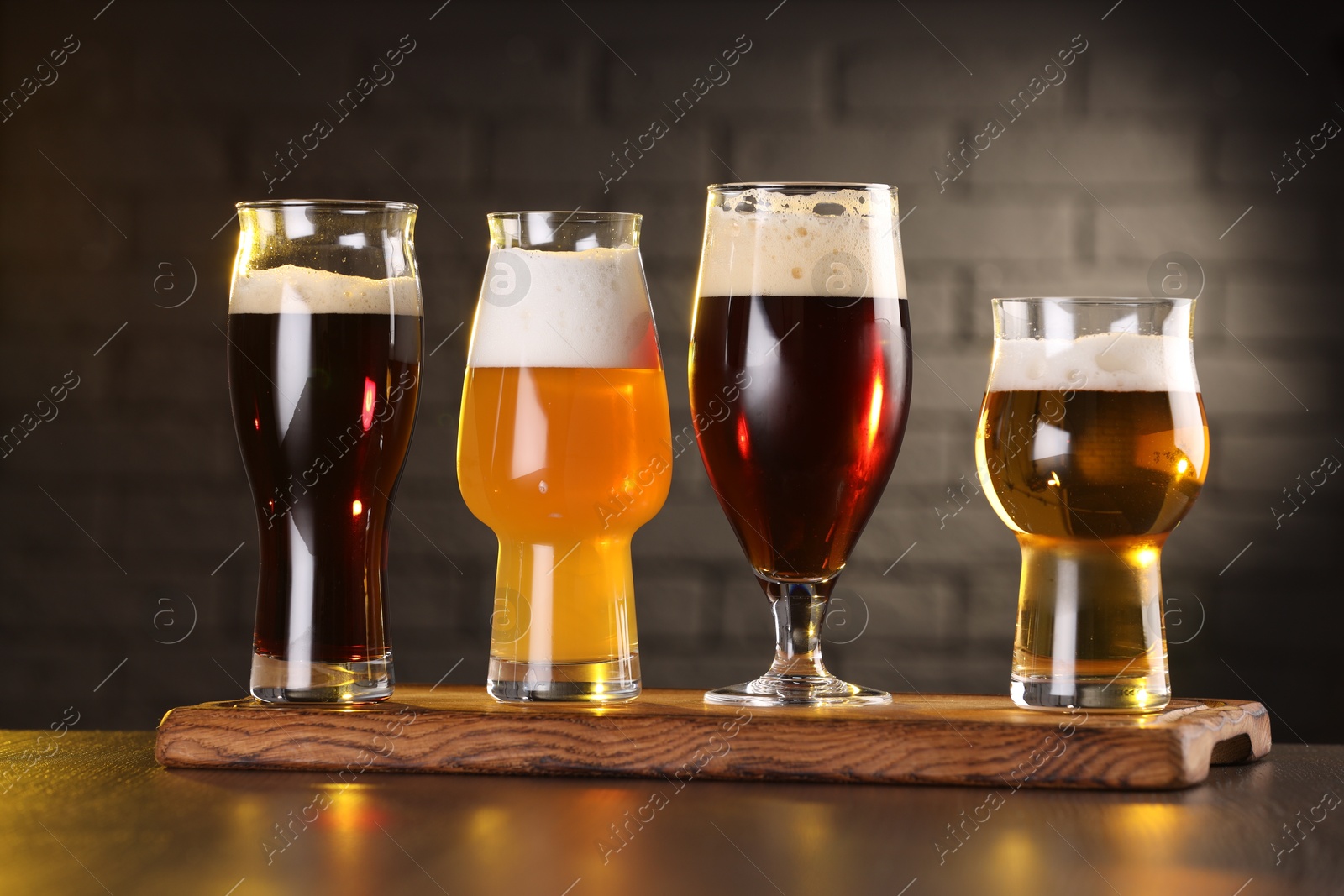 Photo of Glasses with different types of beer on wooden table in bar