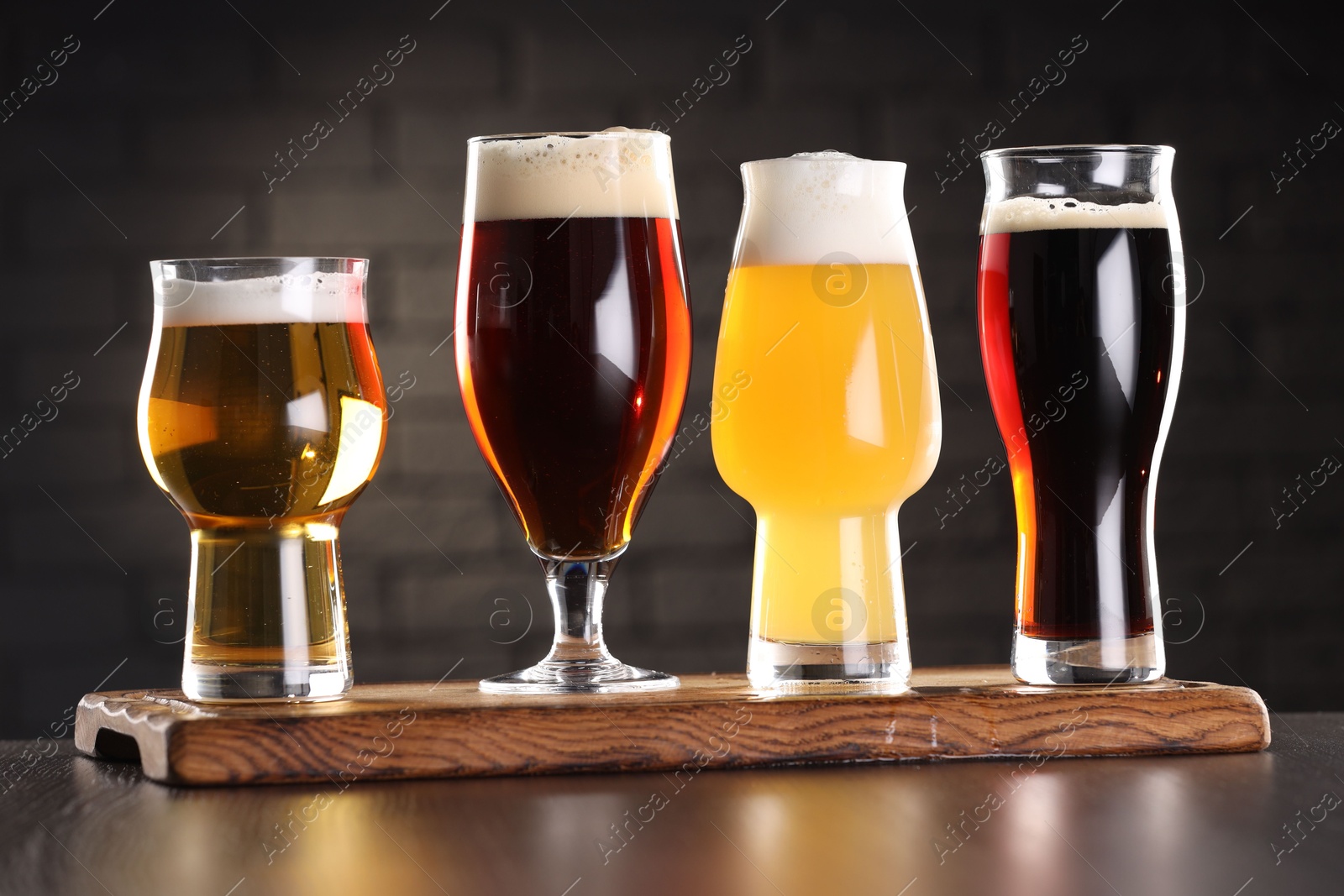 Photo of Glasses with different types of beer on wooden table in bar